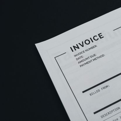 A close-up of an invoice document on a dark background, featuring sections for invoice number, date, amount due, and payment method