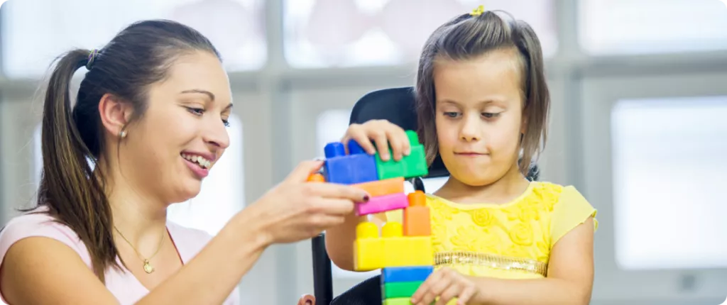 A woman and a girl are playing with colorful building blocks, smiling and engaged in the activity