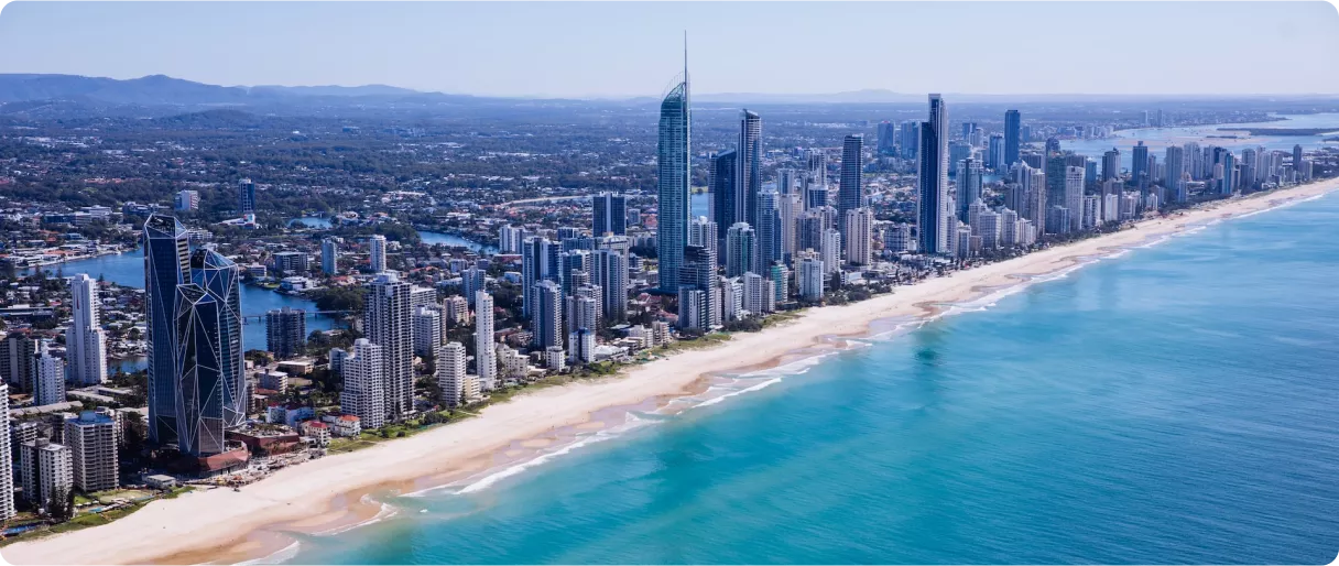 Aerial view of a coastal city with tall buildings, sandy beach, and turquoise waters under a clear blue sky