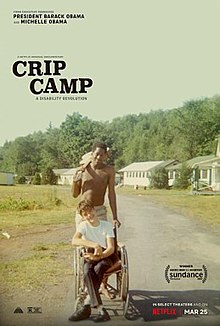 Image is a dirt road with 2 men, one is in a wheel chair. The Image is the cover for Crip Camp: A Disability Revolution netflix documentary.