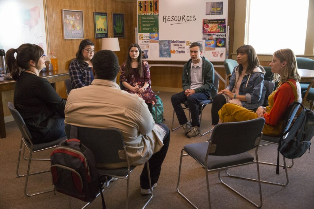 Image is a scene from Atypical TV series. 7 people sit in a cirlce at a peer group about disability.
