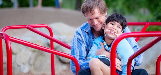 Father smiling holding happy son on playground