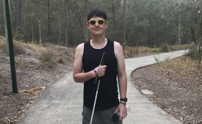 A young man out bushwalking. He stands facing the camera.