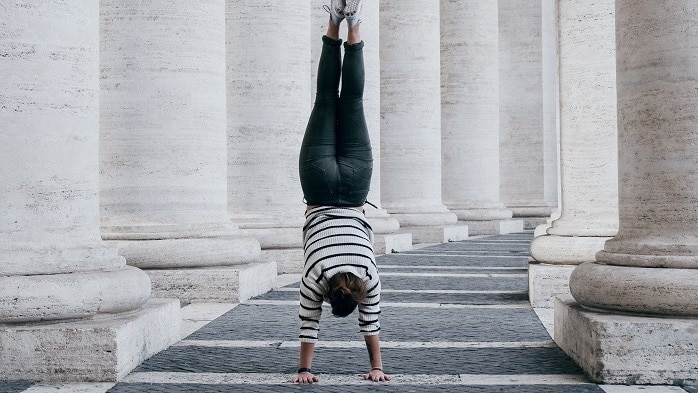 A woman doing a handstand in between the Vatican pillars