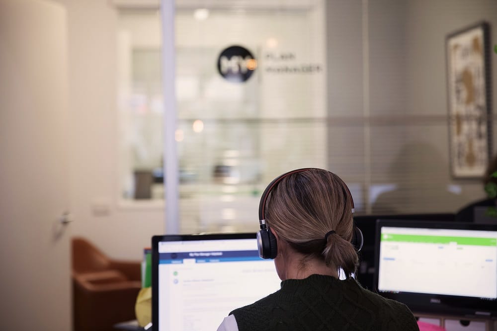 A woman sitting at a computer wearing a headset.