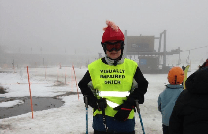 A boy wearing ski equipment with 'Visually Impaired Skier" written on his vest