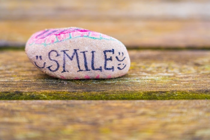 A rock with a hand-painted message on it, which reads 'smile'