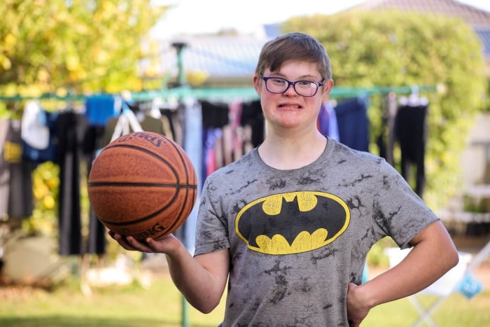 A young man wearing a batman t-shirt holding a basketball
