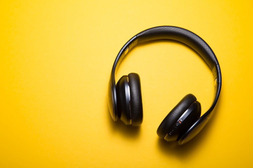 A set of black headphones against a bright yellow background