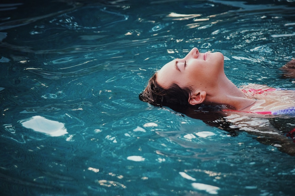 A woman floating peacefully in a swimming pool 