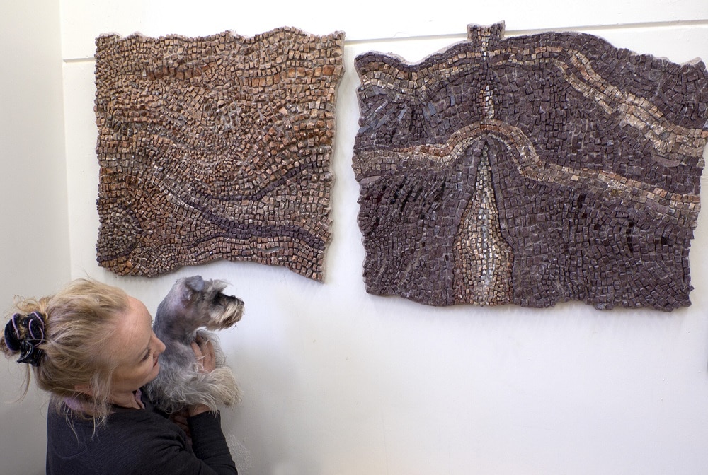 Louise and her assistant dog Penny looking up at her wall-mounted artwork 'Shifting Sand' 2021 and 'Rupture' 2021. 