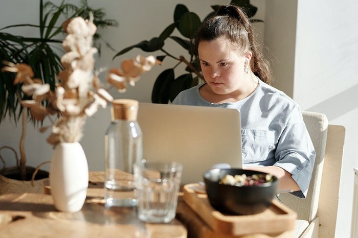 A person sitting at a table in front of a laptop
