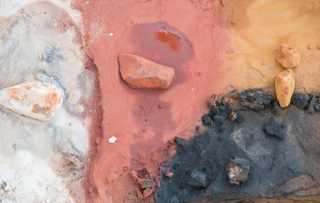 An aerial view of earth and rock in four shades; white, clay, ochre and black.