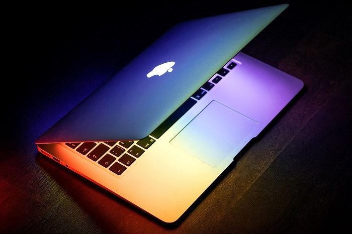 An image of a laptop half closed with a rainbow reflection.