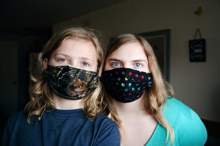 Two young girls wearing face masks, posing for a photo.