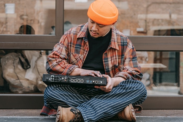 A man sitting on a sidewalk, playing a DJ deck.