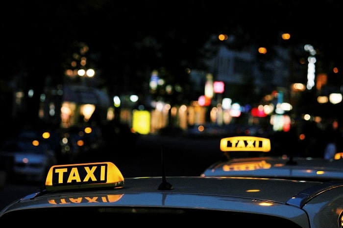 An image of two yellow taxi signs, with a blurred skyline in the background.