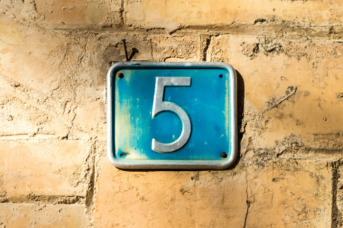 The number five on a blue sign with a brown background.