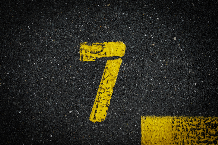 A yellow number seven painted on bitumen.