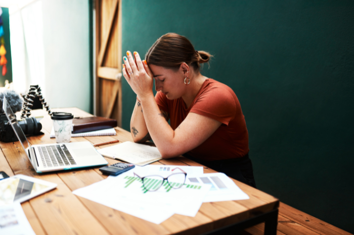 A woman sitting at a desk with her head in her hands.