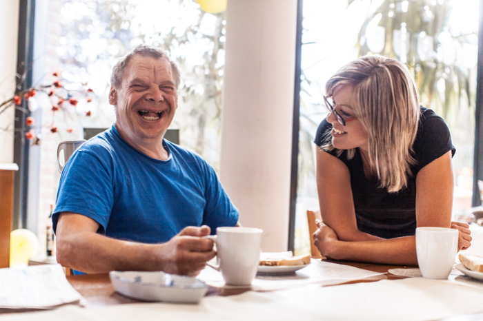 A man in a blue t-shirt and a woman in a black t-shirt enjoy coffee.