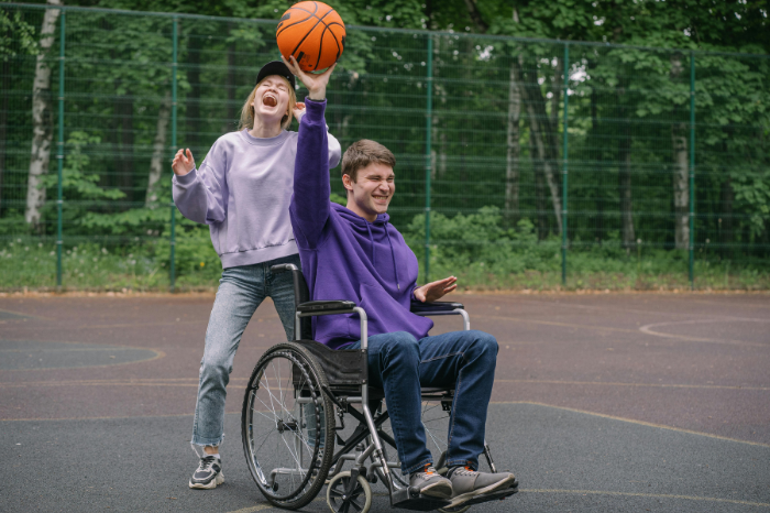 A person in a wheelchair plays basketball with a friend
