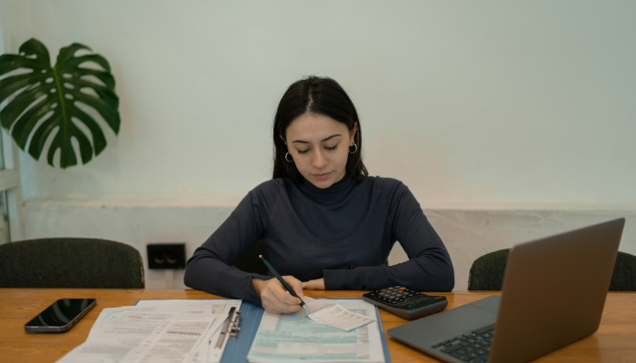 A person working at a desk with a laptop and folder.